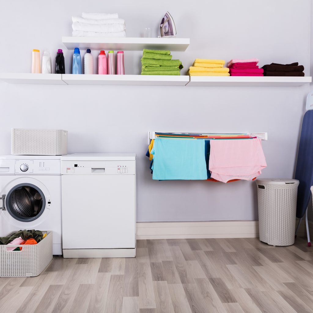 Colorful towels and detergents on high-up shelves in laundry room.