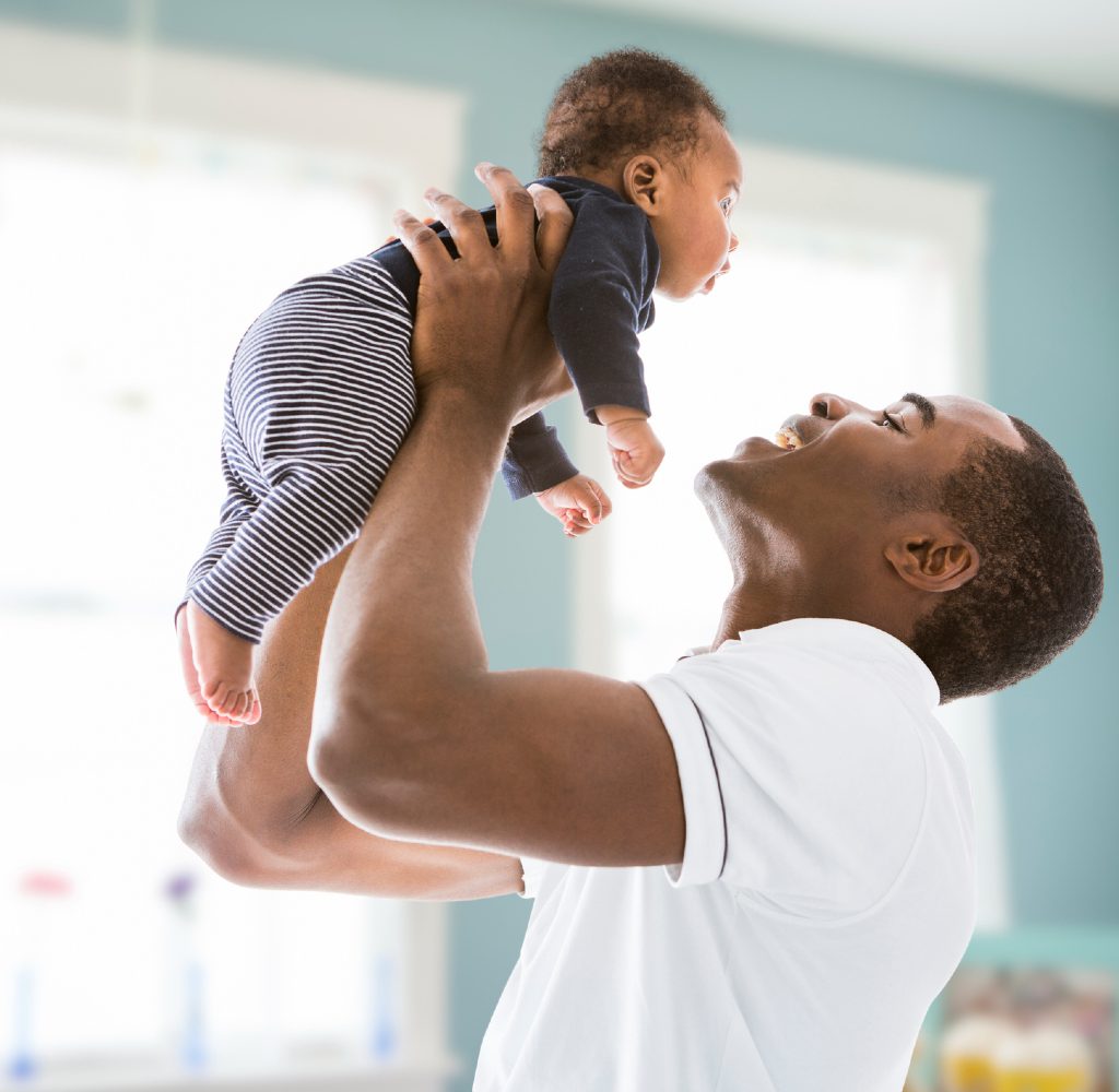 Man with baby in blue nursery.