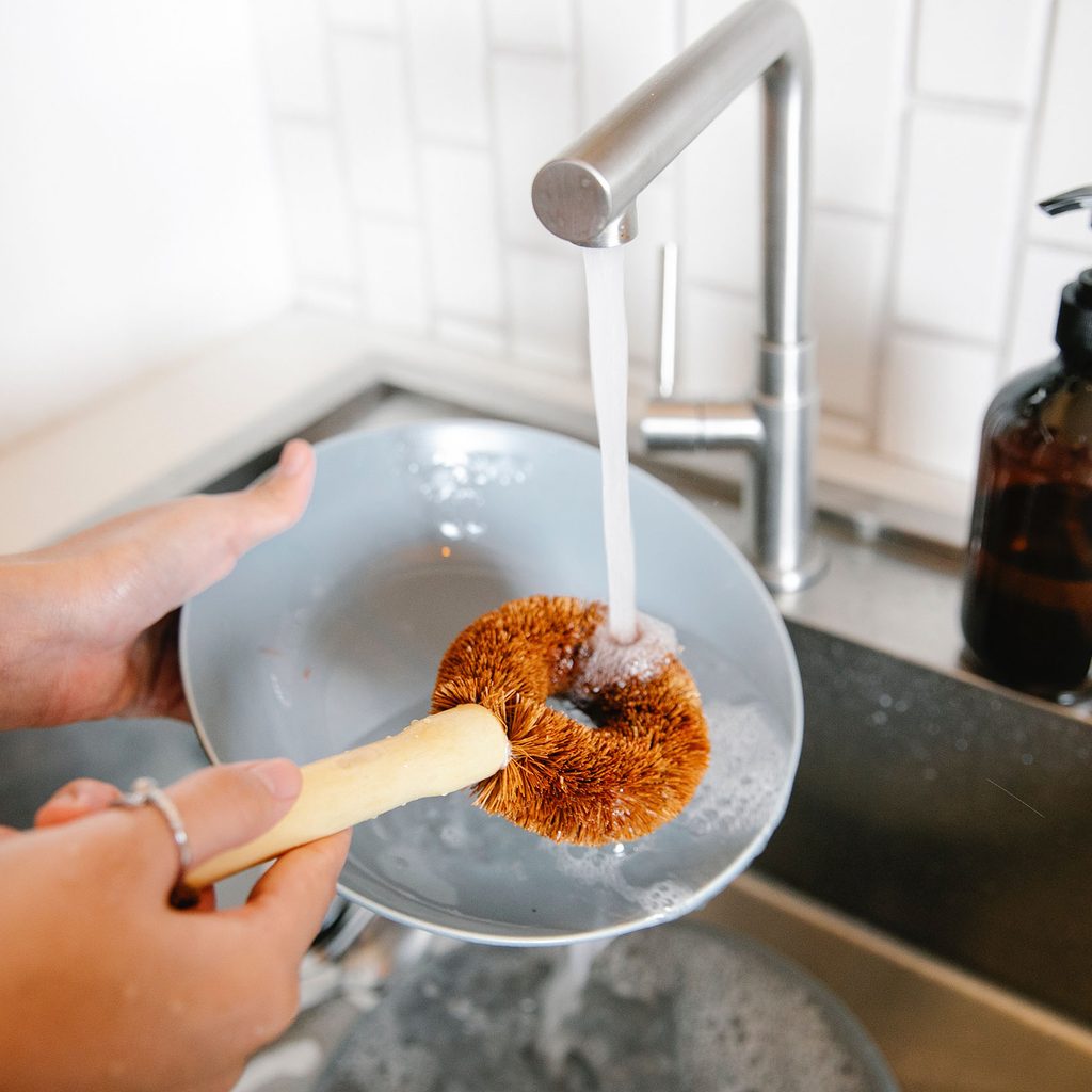 Person washing dishes with a brush