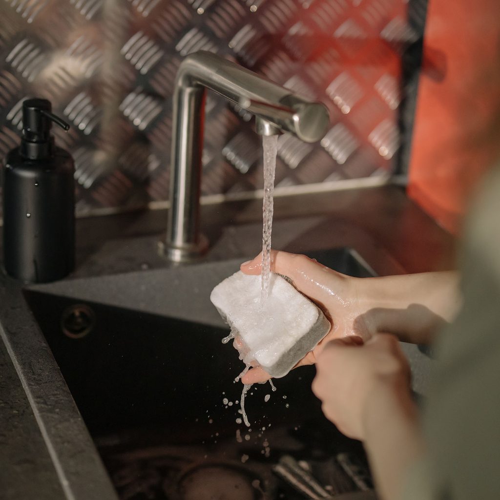 Person washing dishes with a sponge
