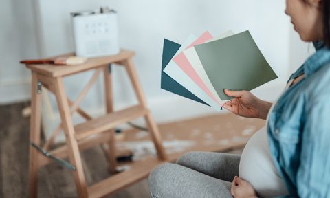 Pregnant woman looking at paint swatches for nursery.
