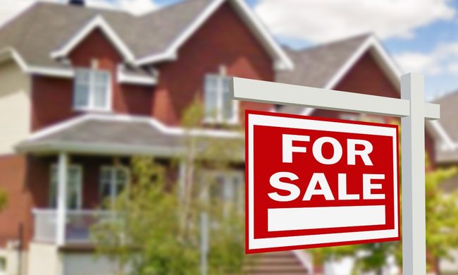 Red house with for sale sign in the front yard