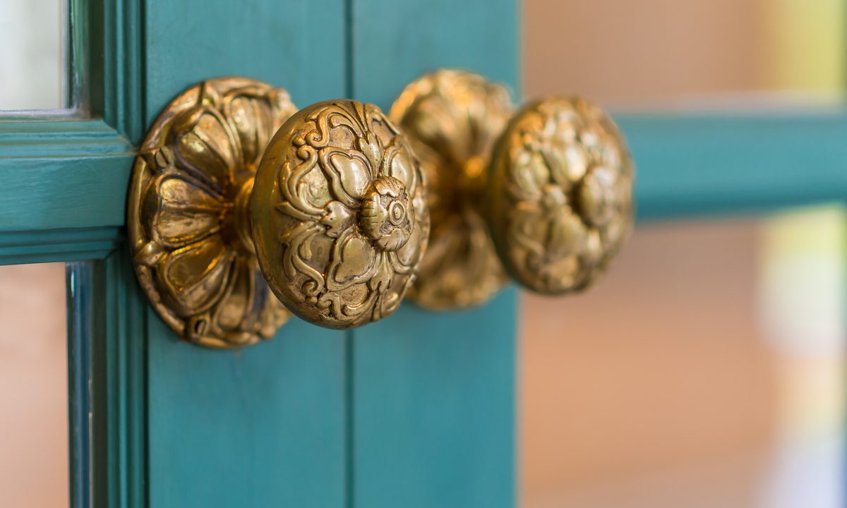 Brass handles on teal cabinet doors