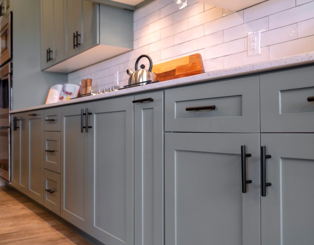 Gray kitchen cabinets with white subway tile backsplash above them