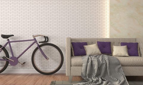 purple bike and couch against white brick wall