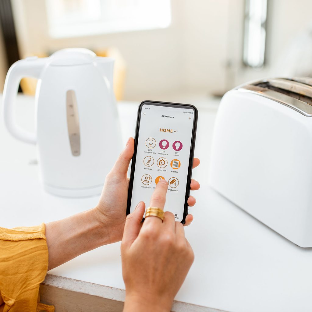 Woman using a smart home device in the kitchen with a toaster