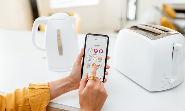 Woman using a smart home device in the kitchen with a toaster