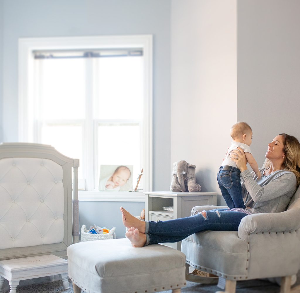 Woman with baby in grey nursery.