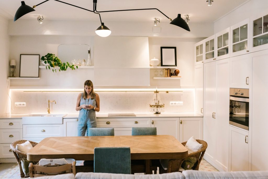 Woman standing in modern kitchen with unique light fixture