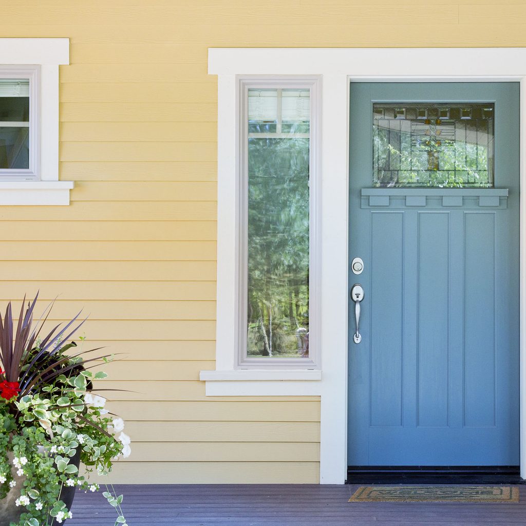 Yellow house with a blue front door and plant