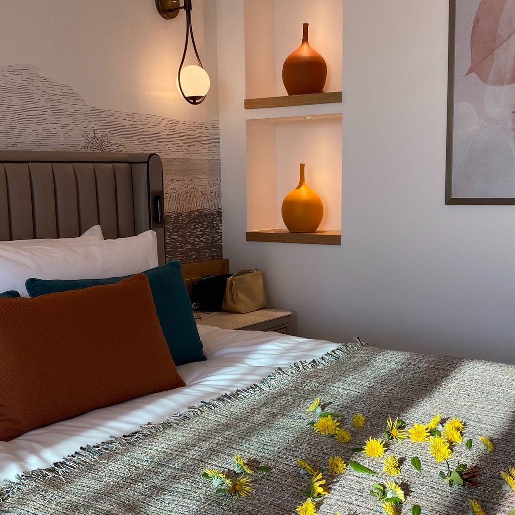 Bed pushed up against a wall with flowers on it