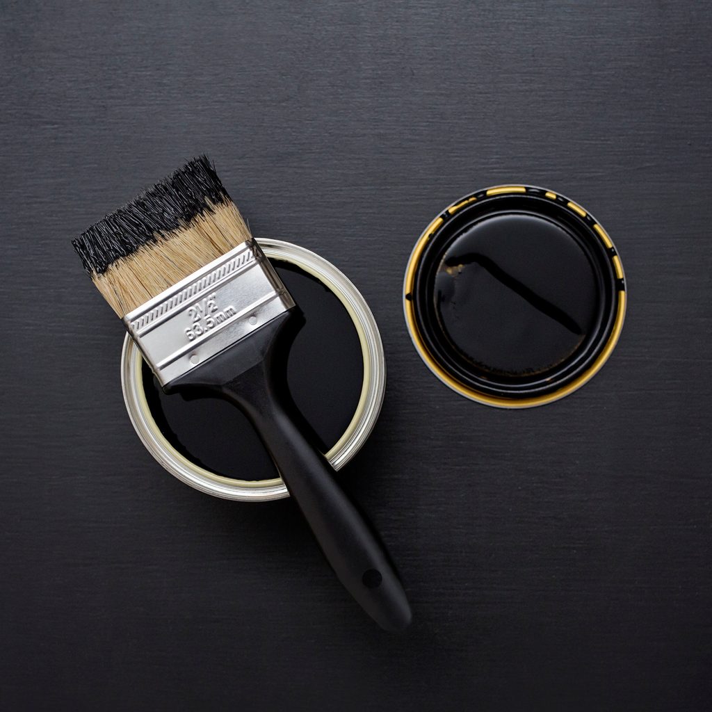 Can of black paint with a paintbrush