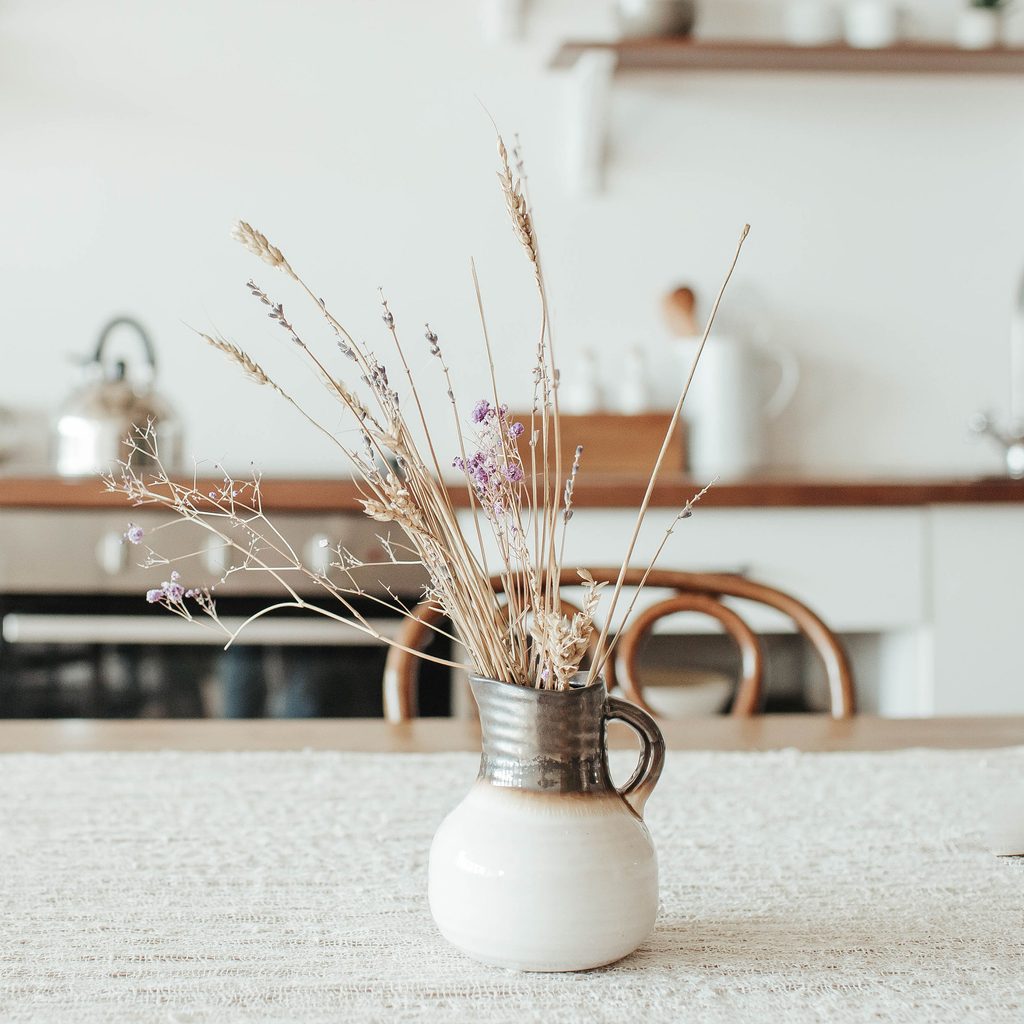 Ceramic jug vase with dried flowers on kitchen counter