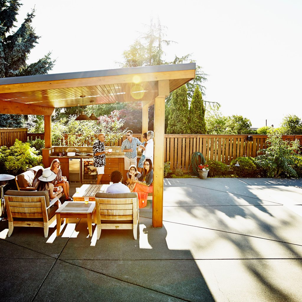 People sitting in poolside gazebo with a grill