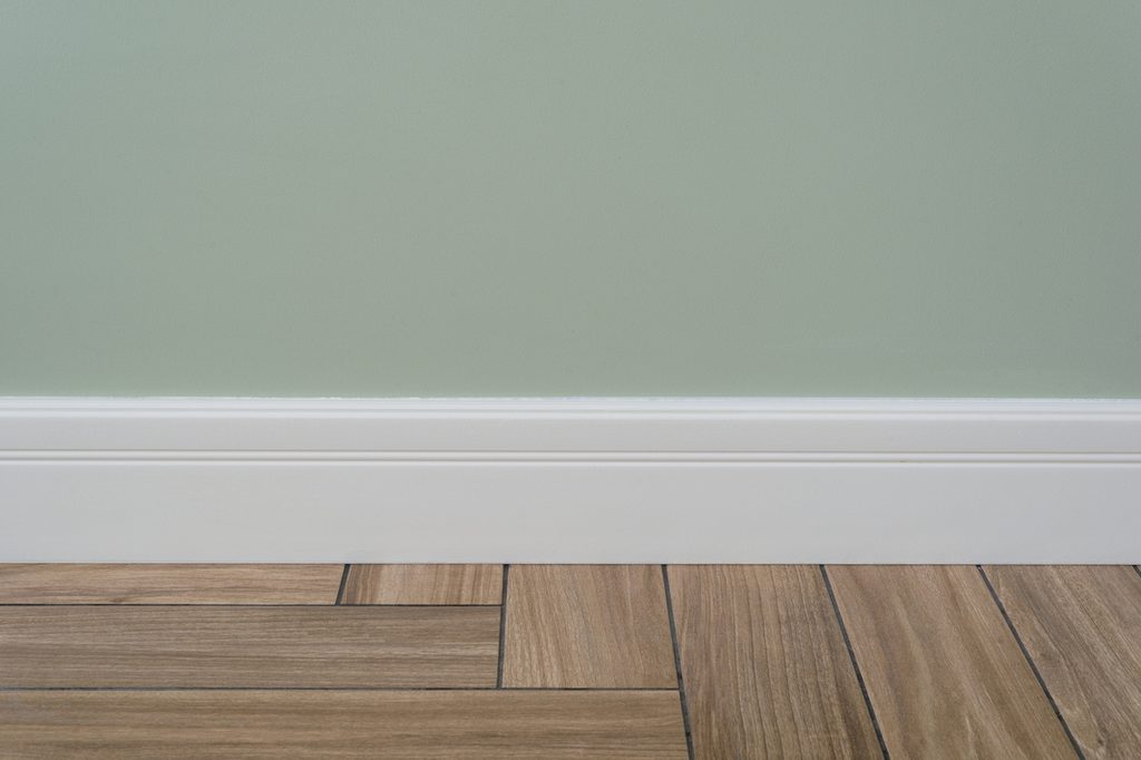 Sage green walls with white baseboard and hardwood floor
