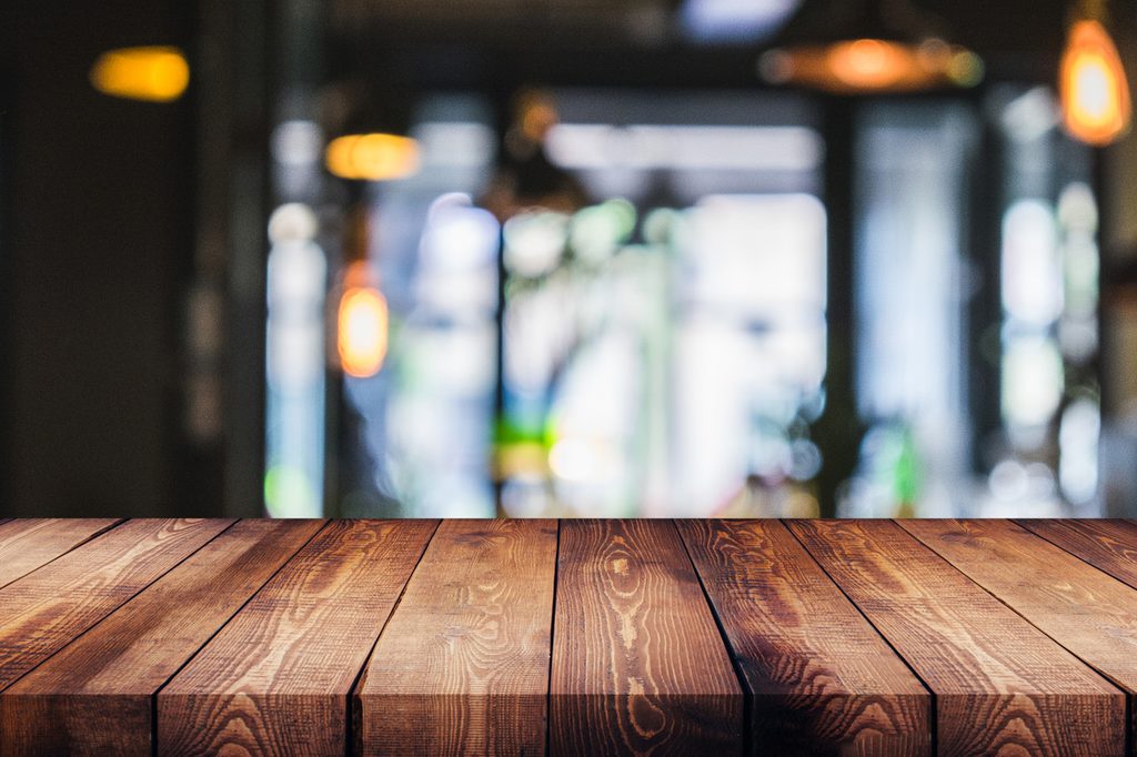 Closeup of rustic wood surface with window and lights in background