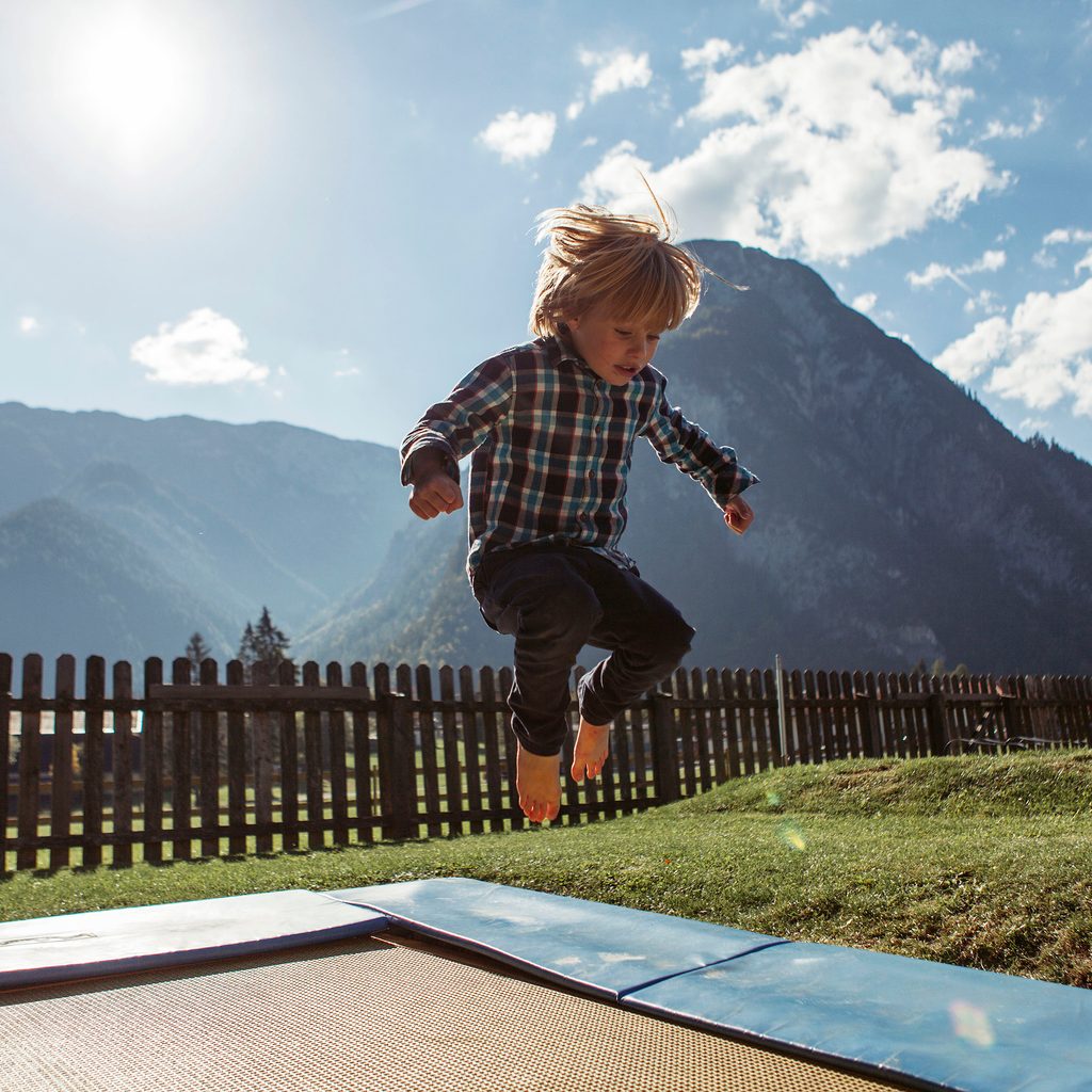 Small child jumping on a trampoline with mountains in the background