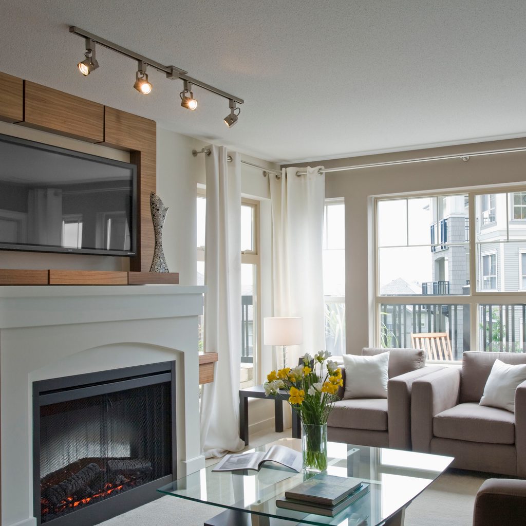 Track lighting used to emphasize tv and fireplace in a living room
