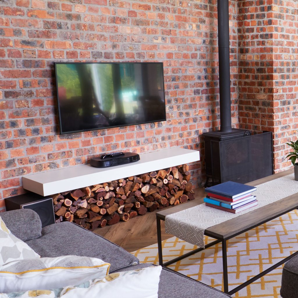 TV mounted on exposed brick wall with a sitting area