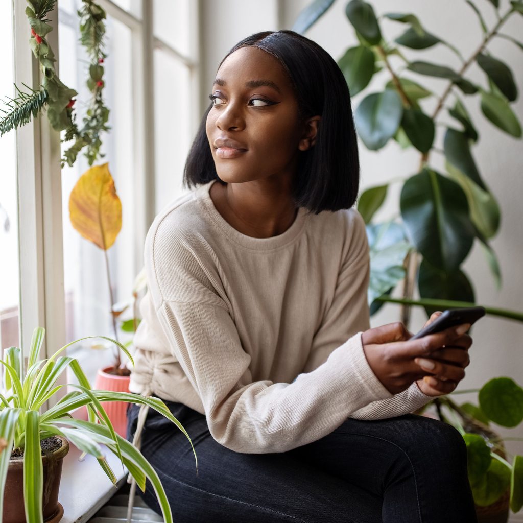 Woman sitting at home surrounded by plants