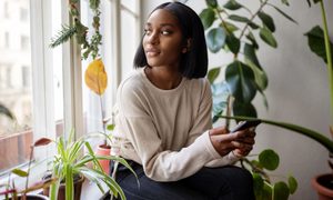 Woman sitting at home surrounded by plants