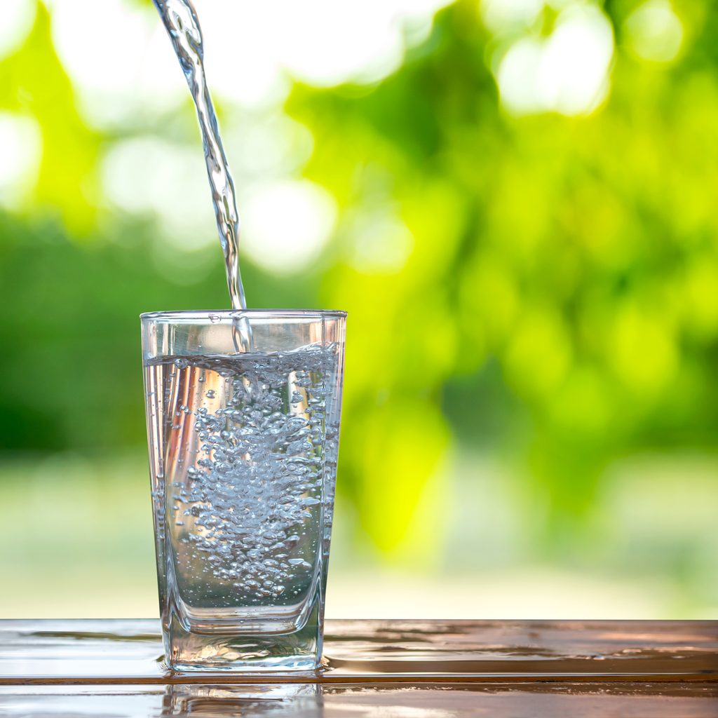 glass water cup with water pouring in