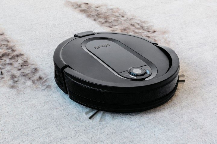 Shark IQ robot vacuum cleaning dirt from white carpet