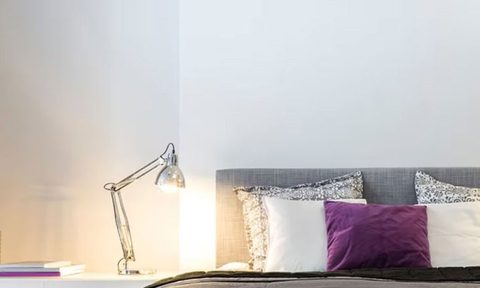 Desk lamp next to bed with gray and purple bedding