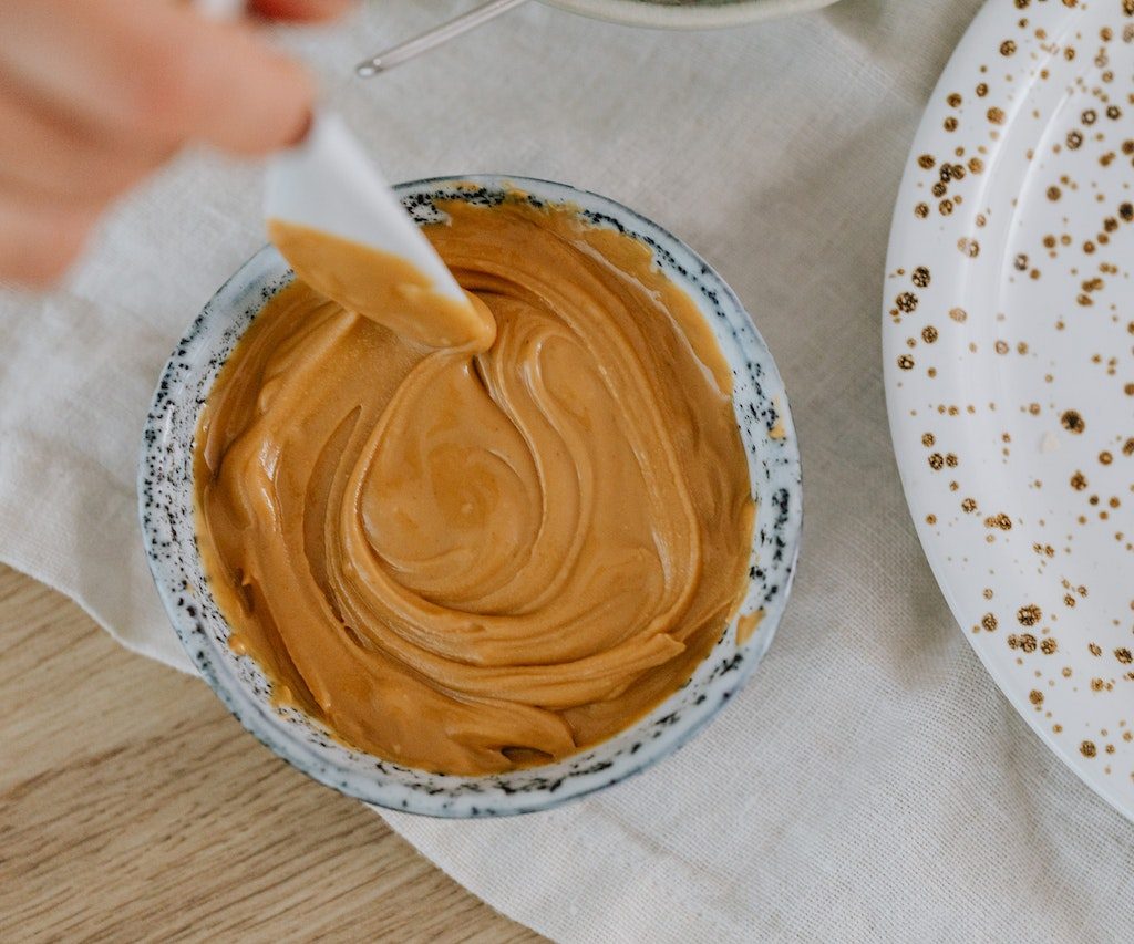 Stirring smooth peanut butter in a small bowl