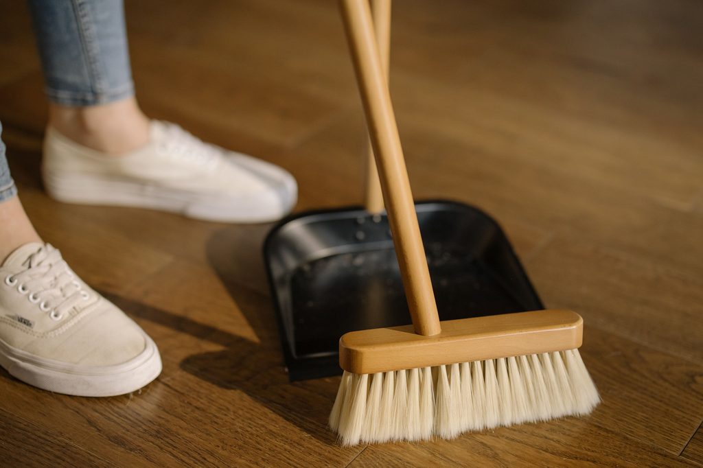 Person sweeping dirt on floor into a dustpan