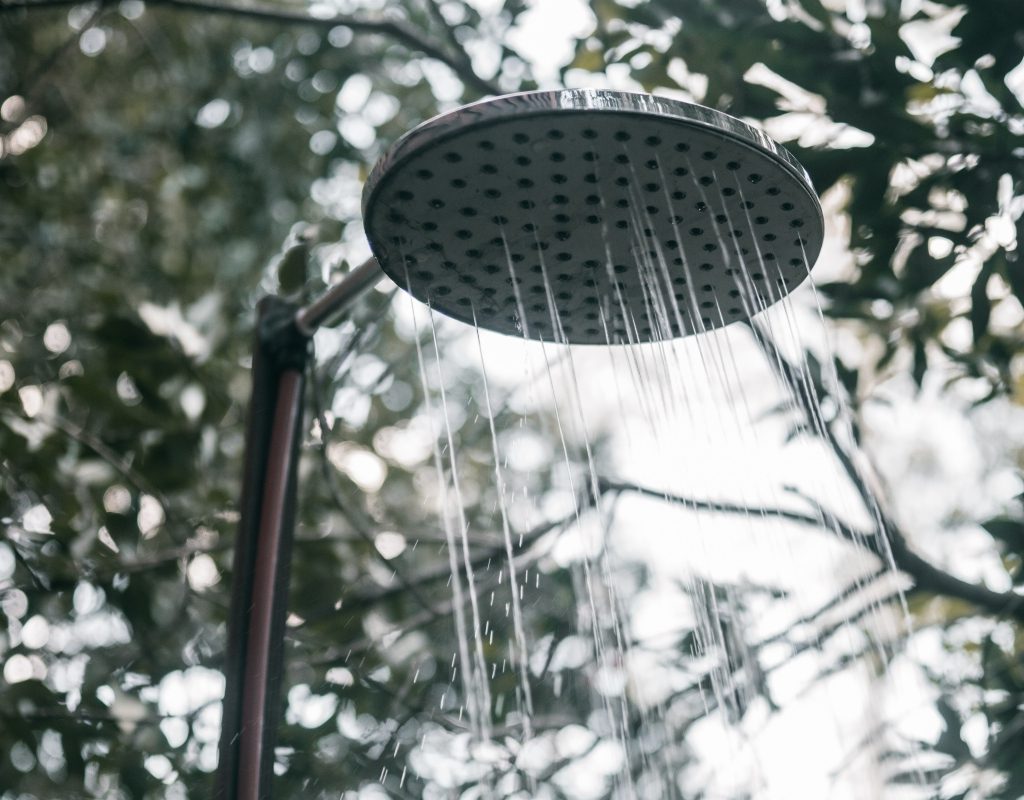 Outdoor rain shower head with trees in the background