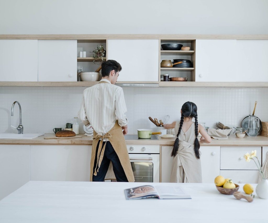 Father and daughter cooking in front of pvc kitchen cabinets