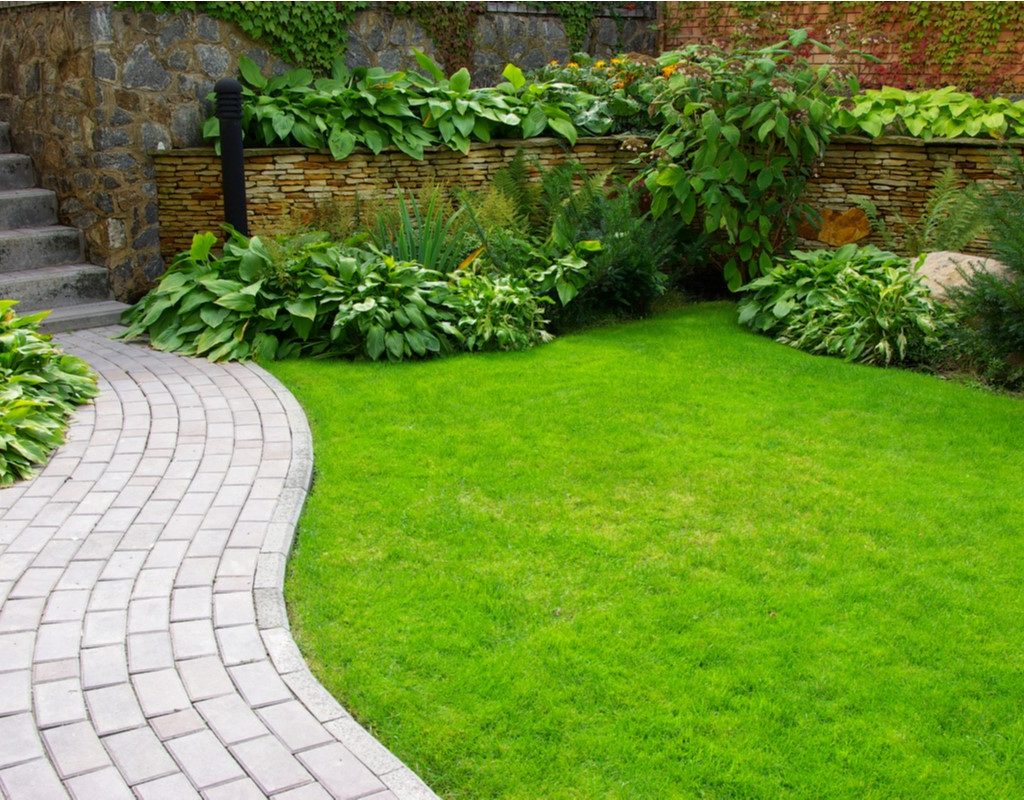 Pristine backyard with brick walkway and stone, ivy-covered walls