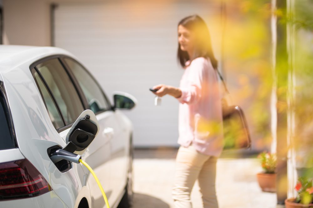 Woman locking an electric vehicle that's on a charger
