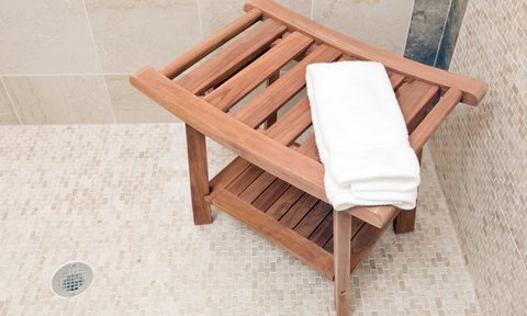 A wooden shower bench with a hand towel on top