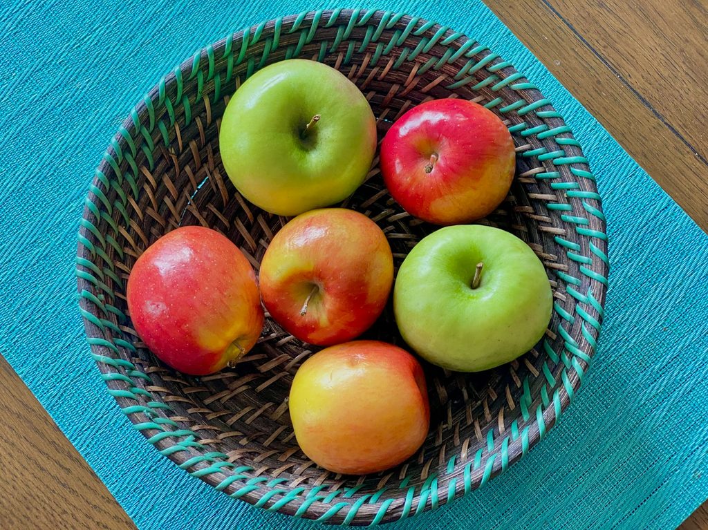 apples in a basket on a blue surface