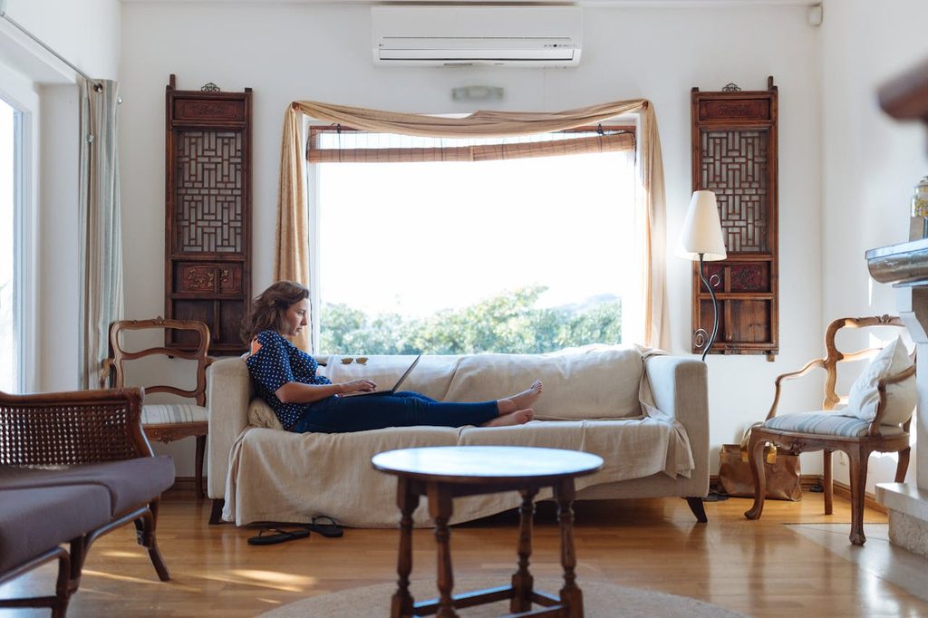 woman lounging on couch in front of window with framed curtains
