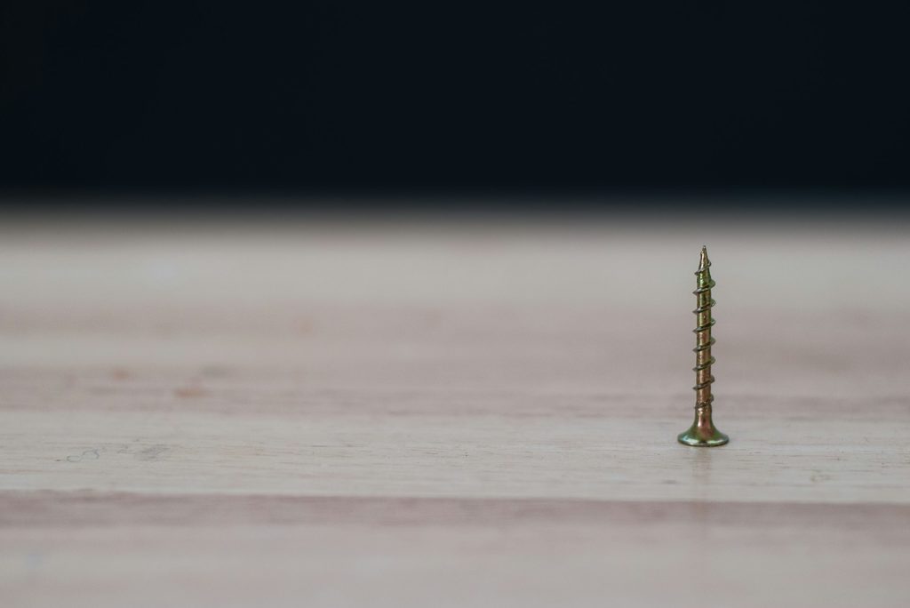 single screw pointed up on a wood surface