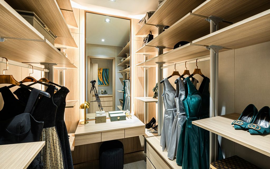 walk in closet with high shelves and a mirror