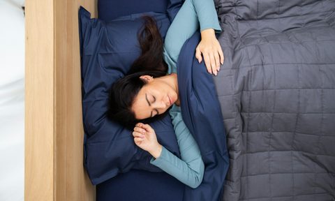 Woman sleeping with gray blanket and navy sheets