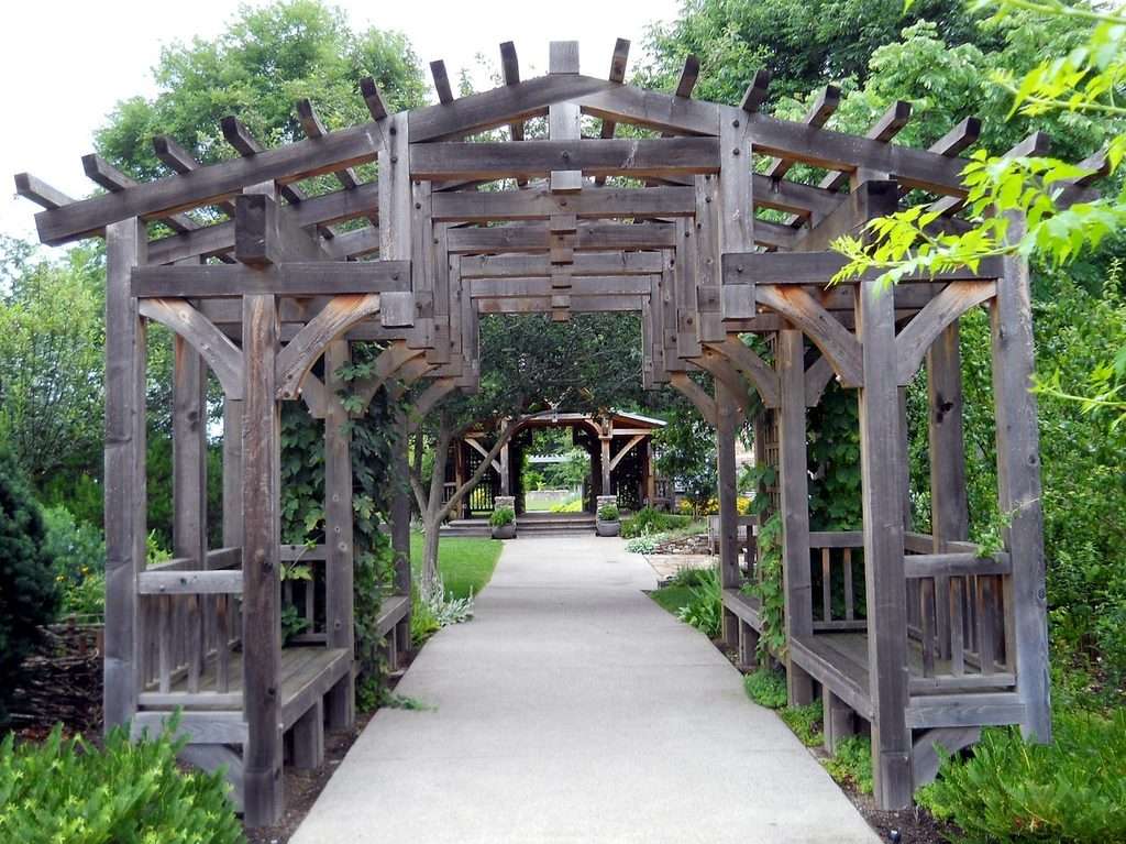 wood pergola with built-in seating along a path