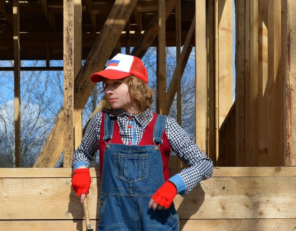 woman posing by a house stud frame being constructed