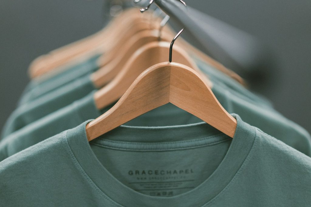 Orderly green garments hanging on wood hangers