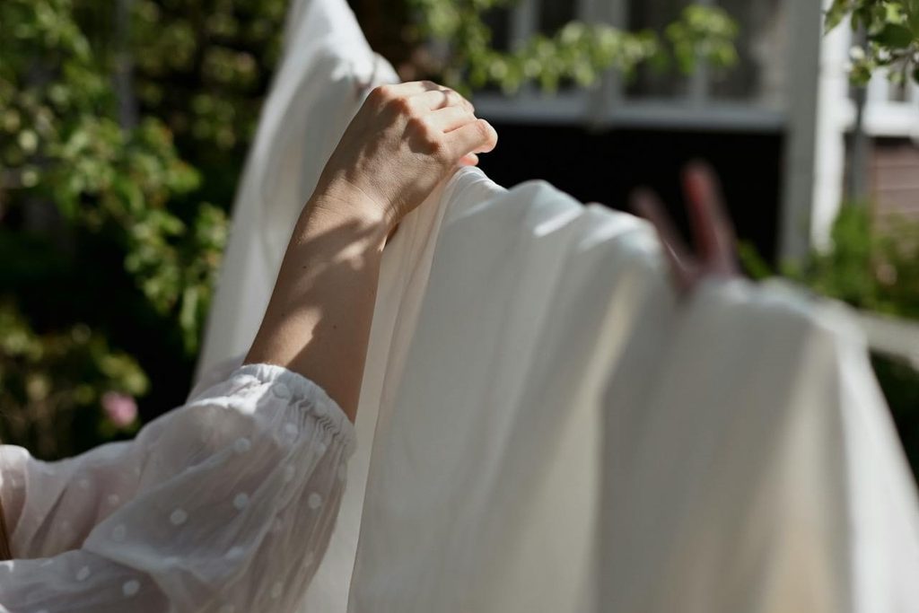 Woman putting white sheets on a clothes line