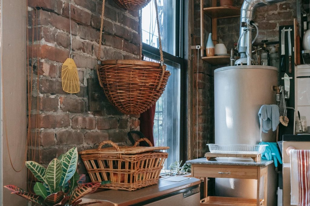 Water heater in kitchen with brick wall and baskets