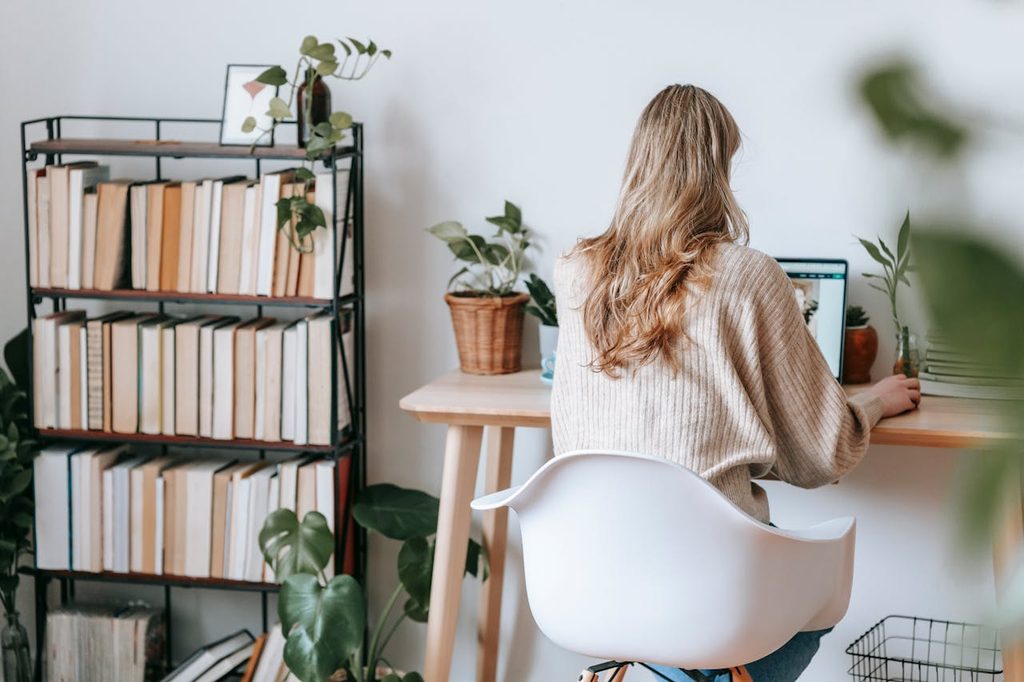 Woman sitting at desk in bright home office with modern bookshelf