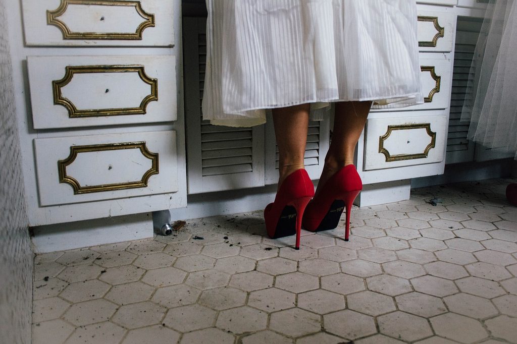 Woman in red heels standing in front of elegant white drawers