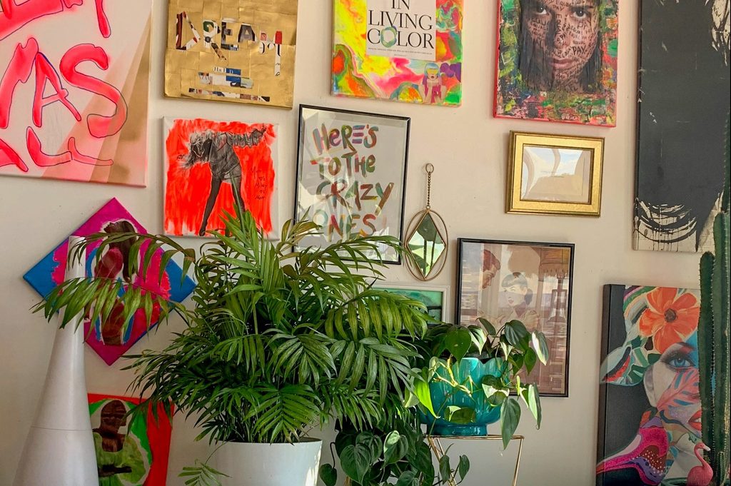 Busy pink wall with multiple photo frames and plants