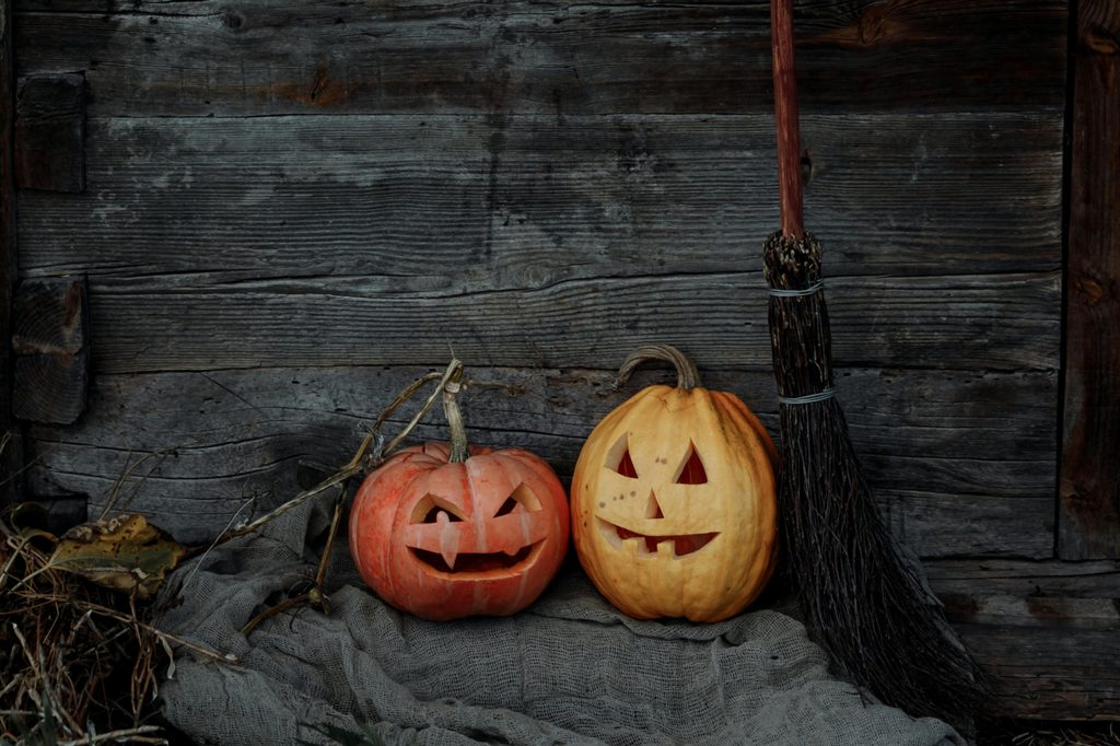 halloween pumpkins and broom by wood wall