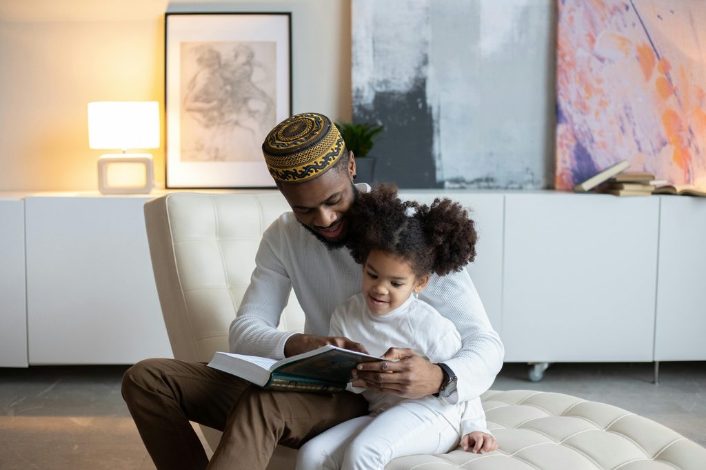 father reading to daughter on chaise lounge